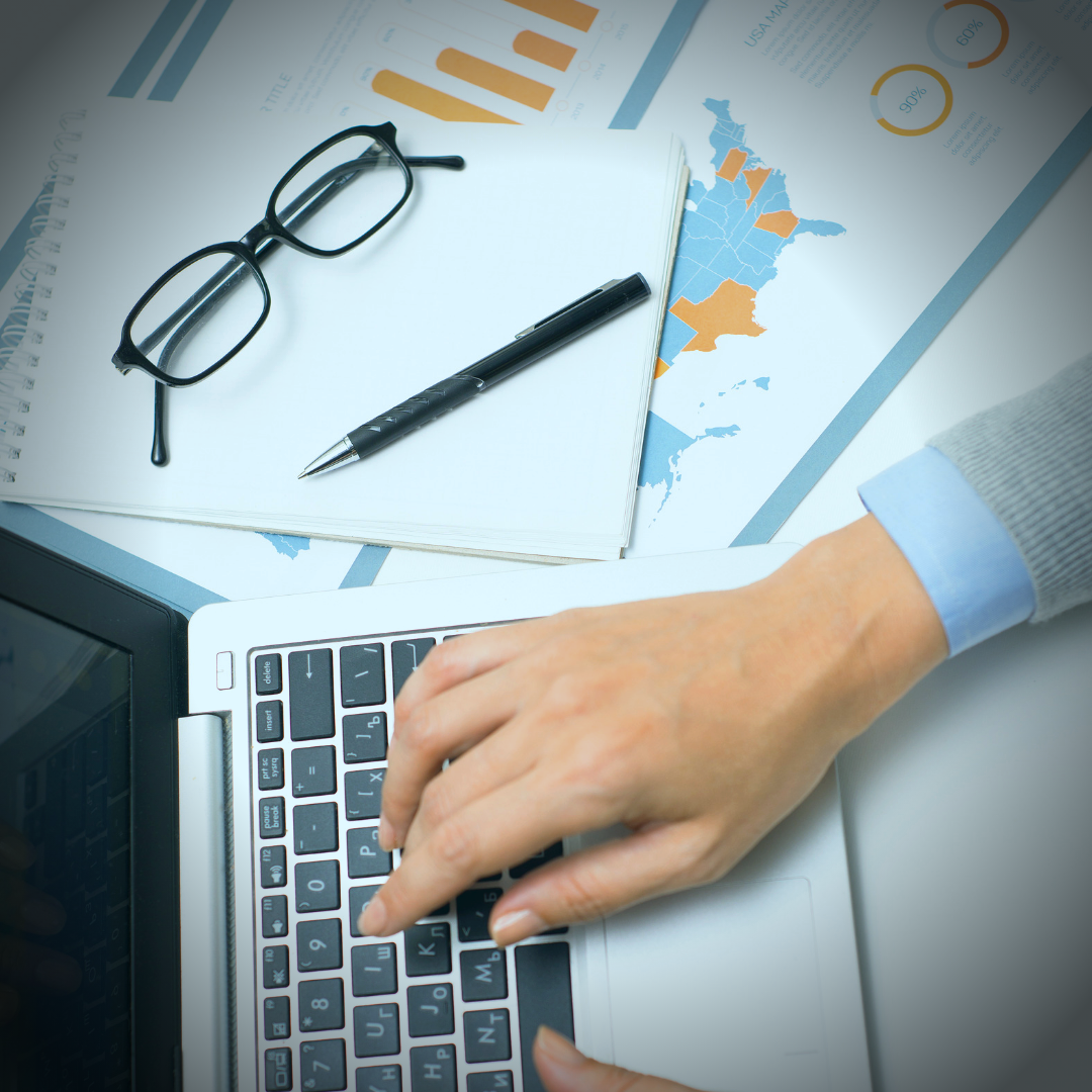 person working at desk with lapstop and research pages on the desk.